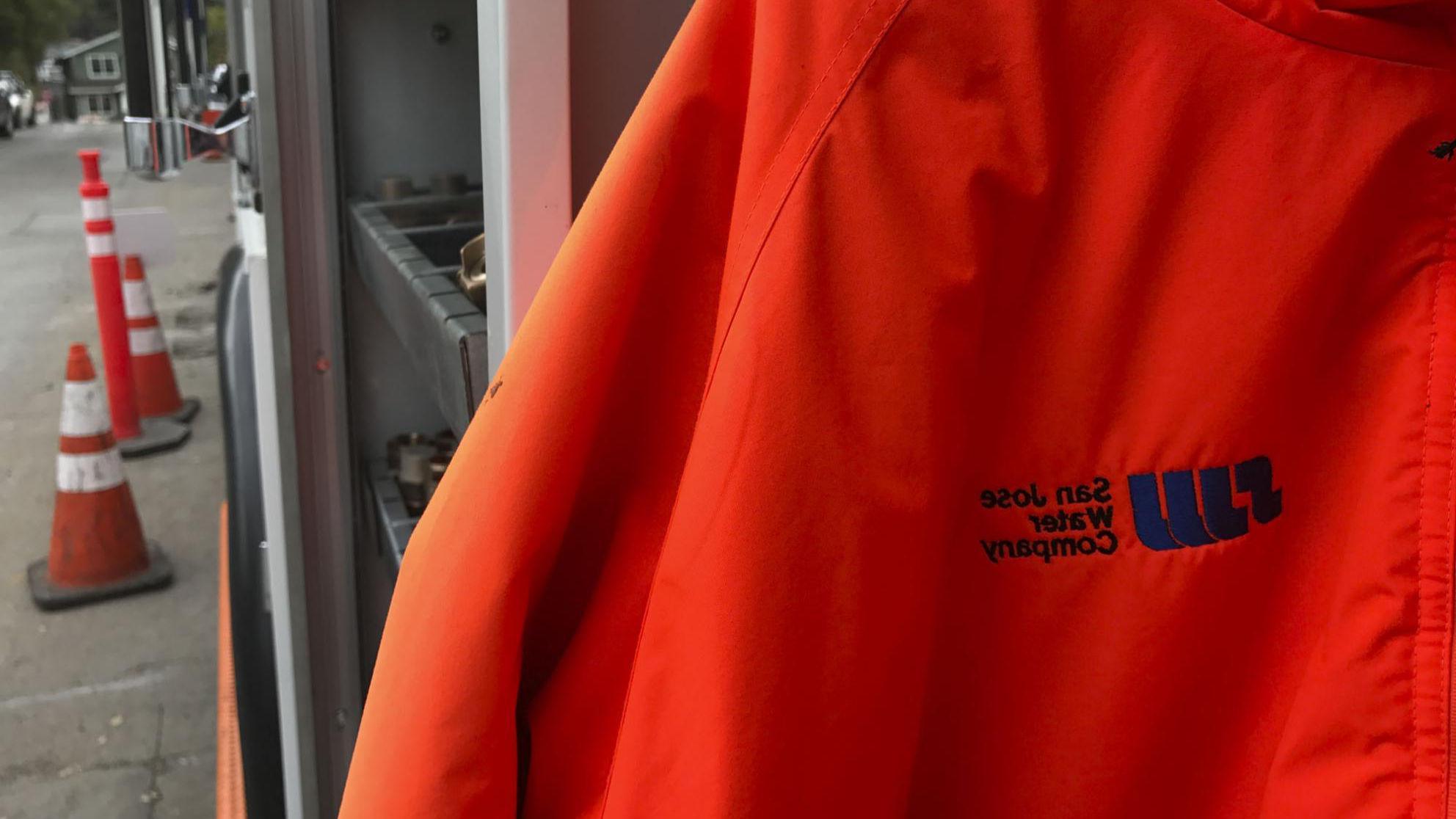 橙色夹克，前景是SJW的标志，背景是高塔